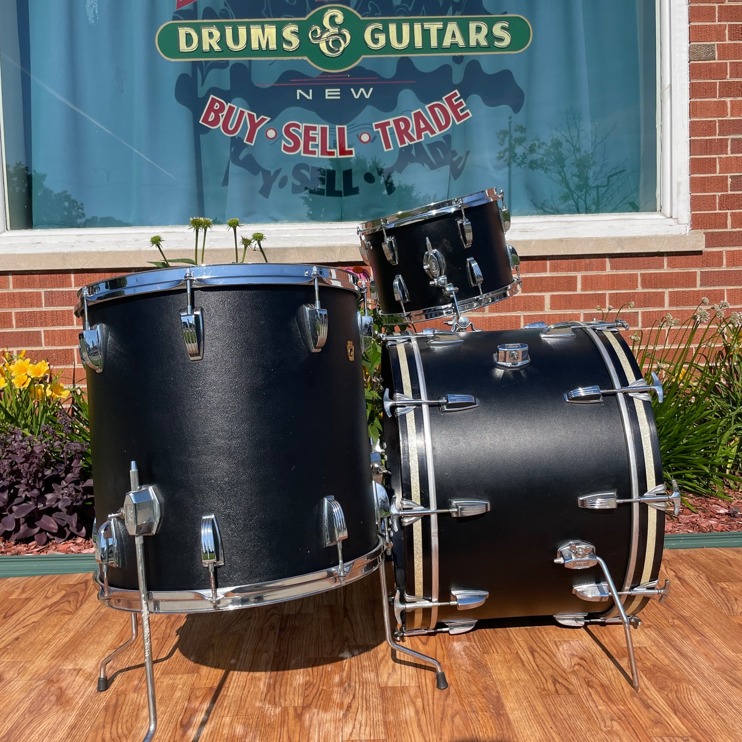 Ludwig Super Classic drum set in Black Panther wrap outside the shop, framed beneath the 'Drums and Guitars / New / Buy Sell Trade' sign