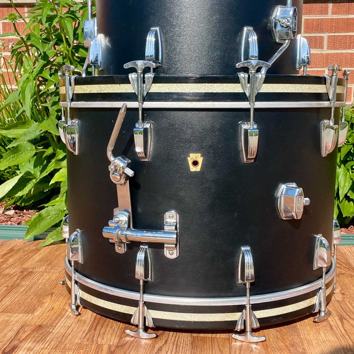 Close-up of the gold Ludwig badge and rail consolette tom-mount bracket on the Black Panther wrap