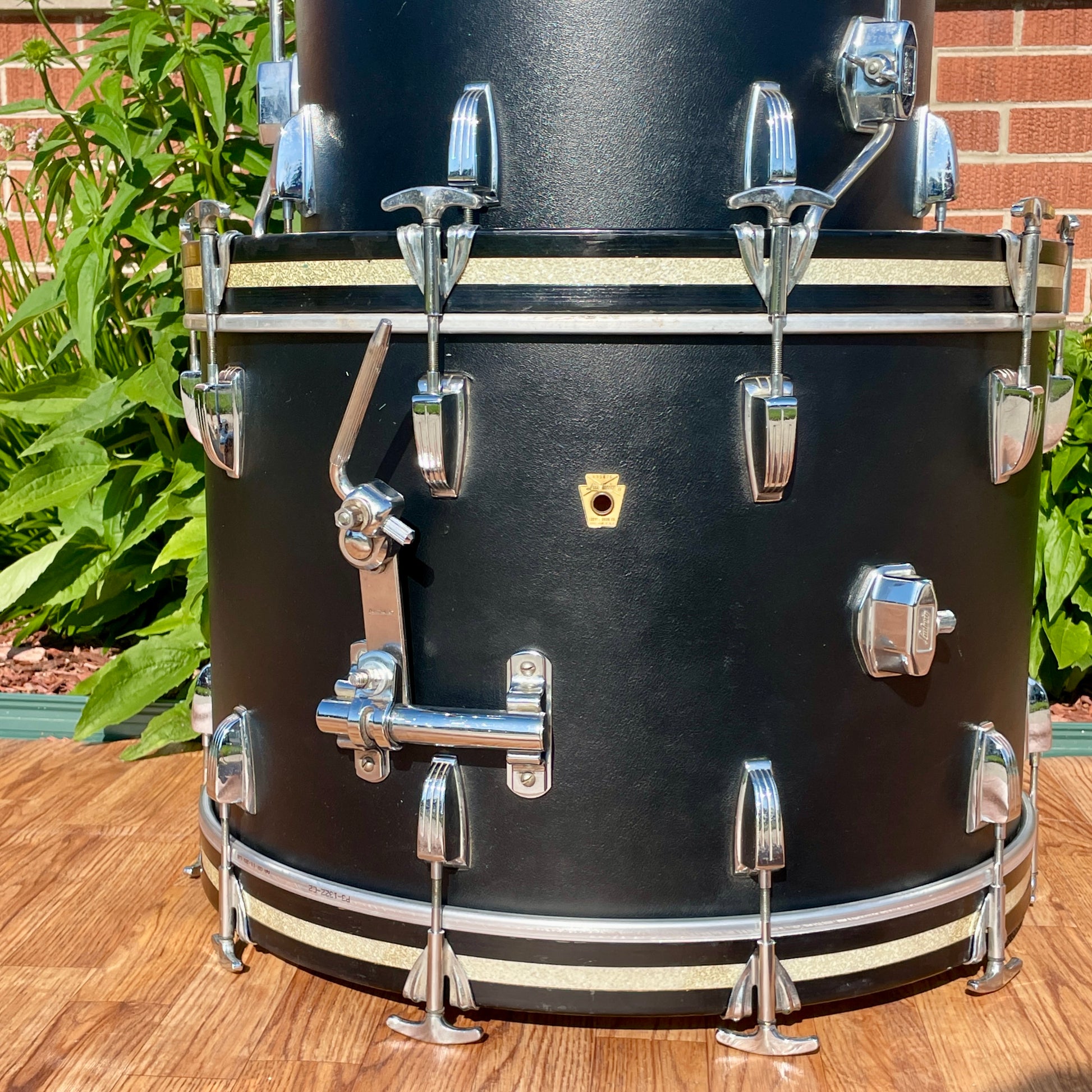 Close-up of the gold Ludwig badge and rail consolette tom-mount bracket on the Black Panther wrap